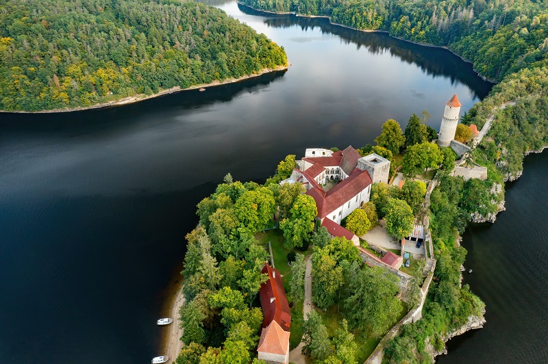 Aerial view of Zvíkov Castle with its traditional red roofs, river, and forest in the Czech Republic.